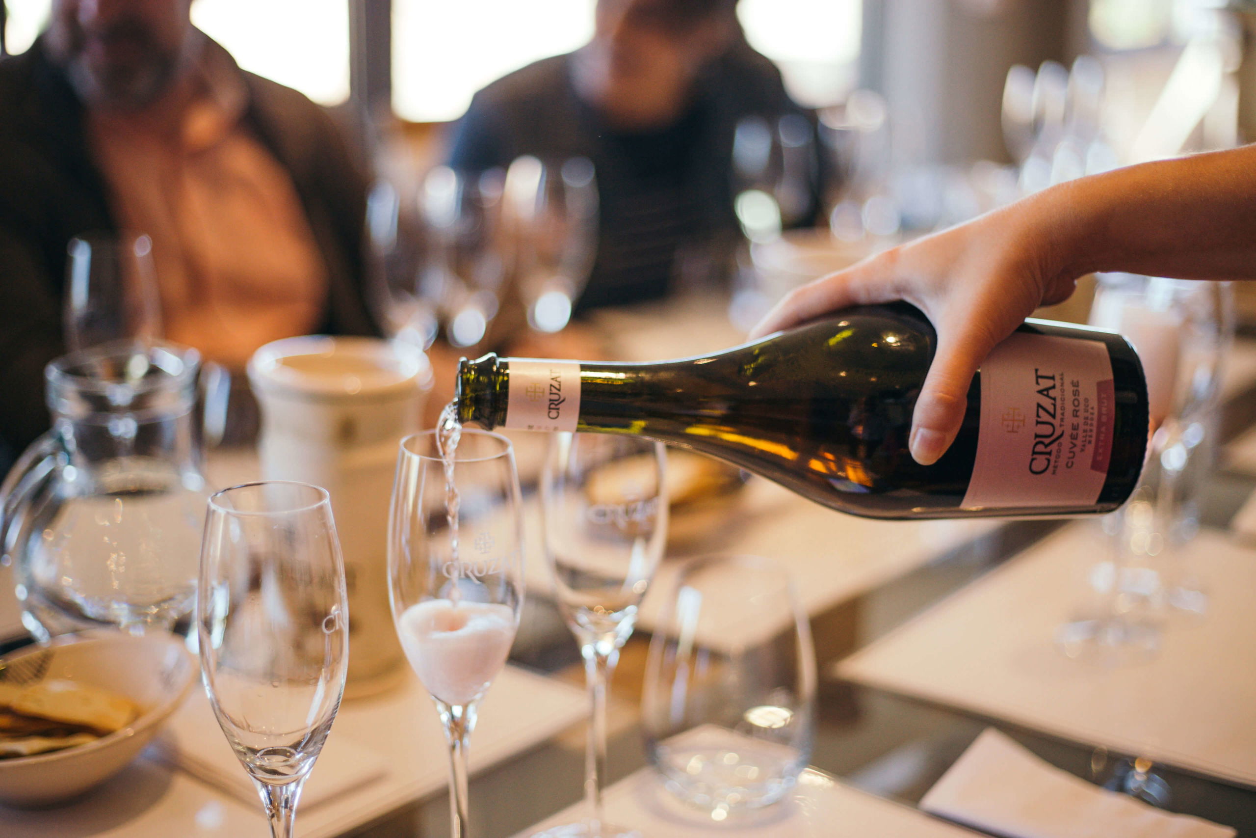 A close-up of a server pouring Cruzat Cuvée Rosé sparkling wine into a glass during a guided tasting in Mendoza, Argentina, a premier stop on a South American luxury wine tour.