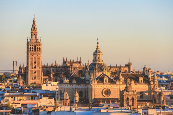 Panoramic view of Seville’s historic skyline at golden hour, featuring the iconic Seville Cathedral and the Giralda Tower rising above the Andalusian cityscape.