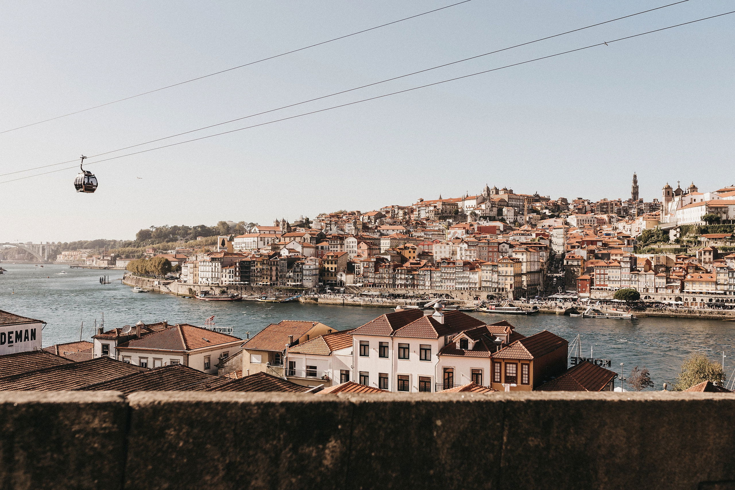 A scenic view of Porto’s historic Ribeira district, the Douro River, and cable cars above the cityscape.