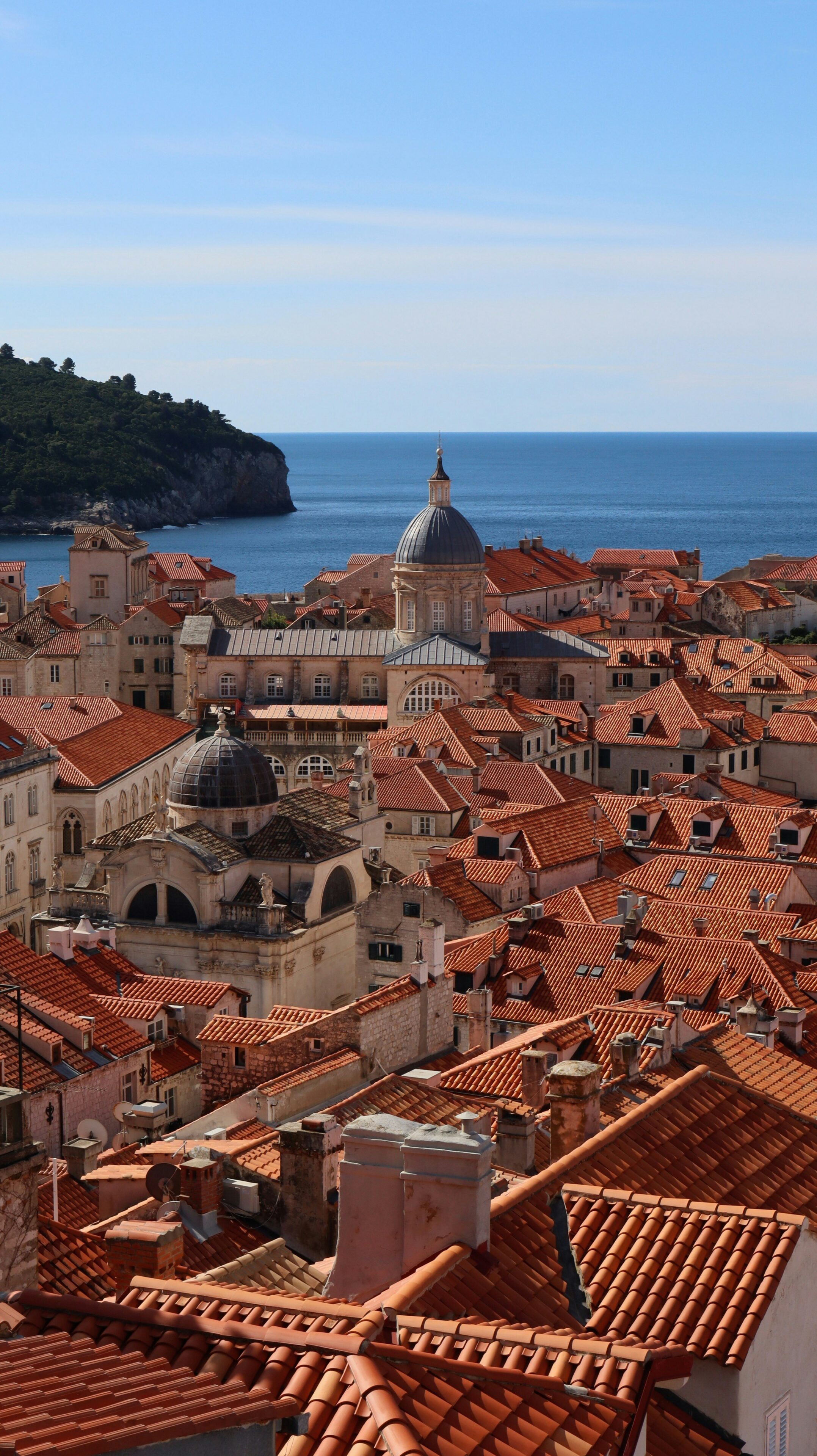 Elevated view of Dubrovnik’s terracotta rooftops and historic dome architecture set against the Adriatic Sea.