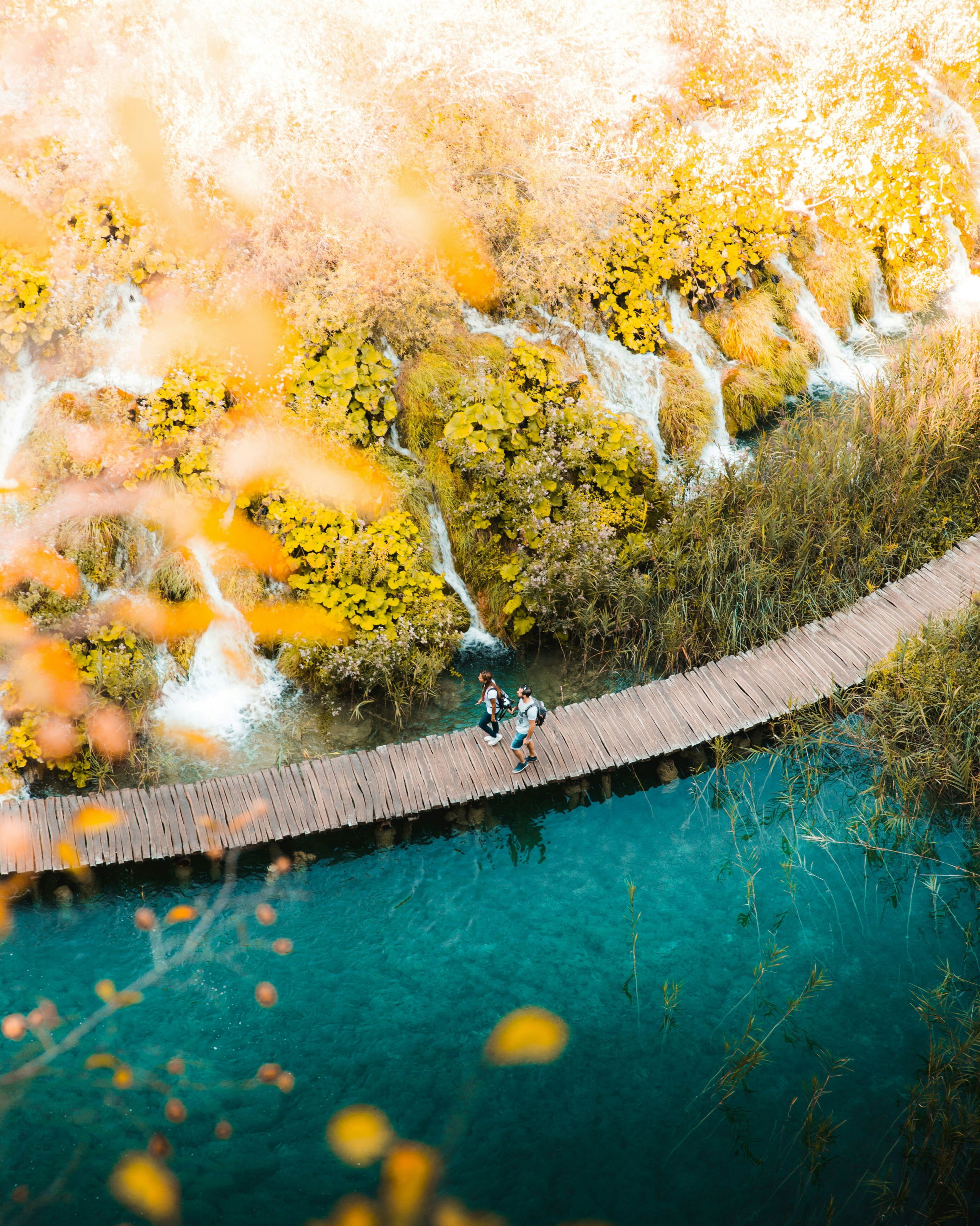 A family walking along a wooden path through turquoise lakes and waterfalls at Plitvice National Park during a luxury family trip to Croatia.