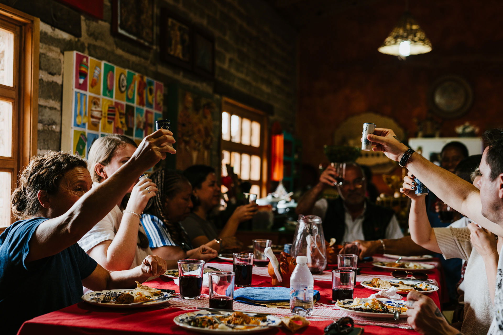 People sit at a long table sharing a meal and raising glasses in a toast.” Kept it neutral, descriptive, and focused on what’s visually clear.